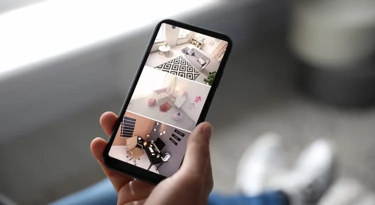 Personne en vacances surveillant sa maison sur un smartphone via une caméra de sécurité.