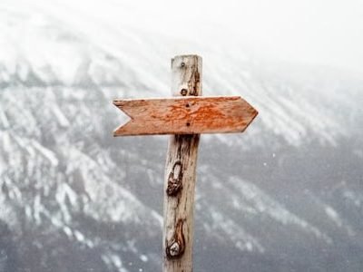 pexels-photo-66100-66100 A wooden arrow signpost points the way amidst a snowy mountain landscape.